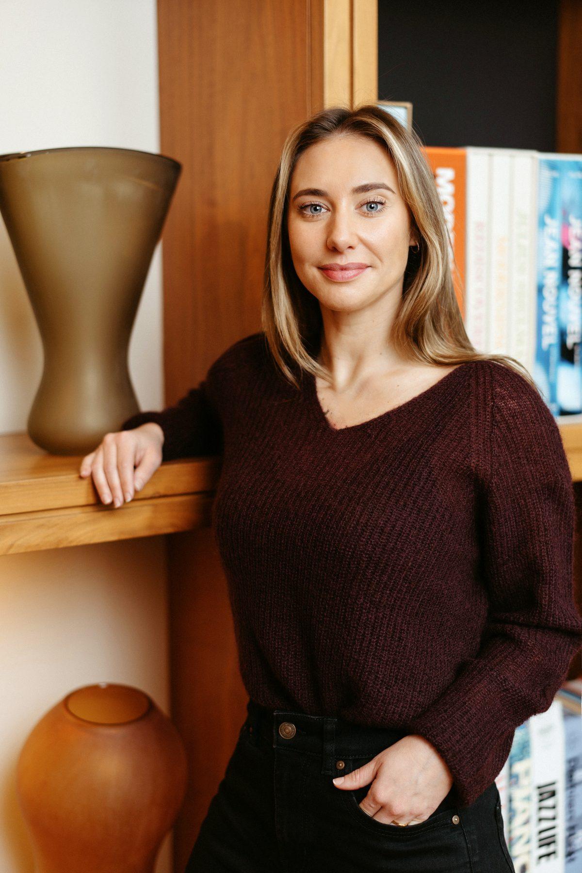 Jemma Dennis, standing beside a bookshelf in her consulting room